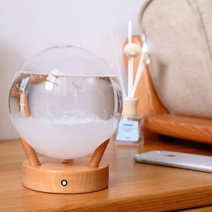 Etherische olie diffuser in de vorm van een globe, geplaatst op een houten tafel, met een modern bureau- of woonkamerdecor.