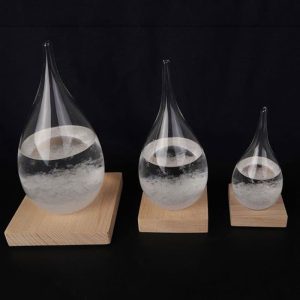 Glazen pipetten met een transparante vloeistof, gerangschikt op houten standaarden van verschillende groottes, illustreren een wetenschappelijk fenomeen of een laboratoriumexperiment.