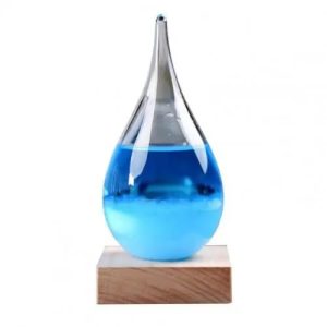 Glazen pipet met een blauwe vloeistof, geplaatst op een houten voet, gebruikt als wetenschappelijk decoratieobject of voor educatieve experimenten.