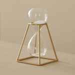 Glazen tijdhouder met een gouden frame, elegante en moderne wetenschappelijke decoratie, ideaal voor liefhebbers van industrieel design en wetenschappelijk geïnspireerde decoratieobjecten.