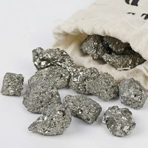 Glanzende en metalen pyrietklomp, afkomstig uit een wetenschappelijke verzameling, gepresenteerd op een witte oppervlakte met een canvas tas op de achtergrond.