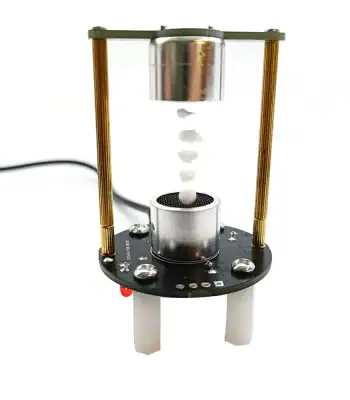 Miniatuur wetenschappelijk apparaat dat een experiment met knikkers en een glazen cilinder illustreert, perfect voor decoratie of wetenschappelijke educatie.